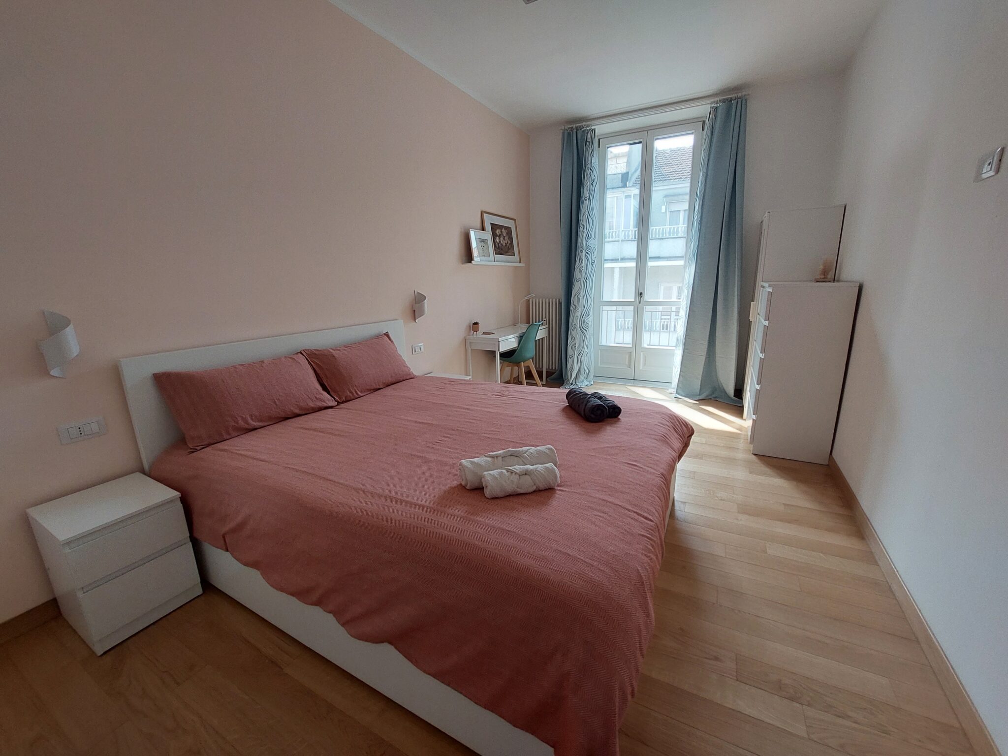 Camera da letto con copriletto rosa e ampia finestra | Casa Vacanza San Salvario